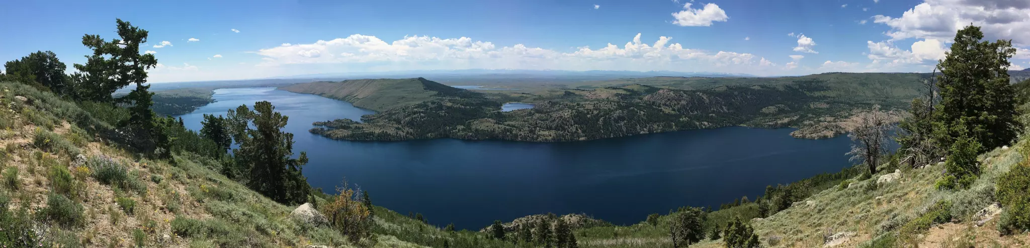 Panorama of deep blue Fremont Lake between sagebrush hills and pines under a summer sky