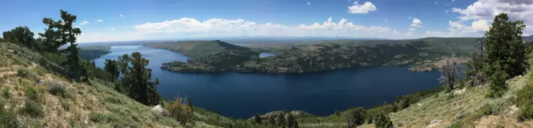 Panorama of deep blue Fremont Lake between sagebrush hills and pines under a summer sky